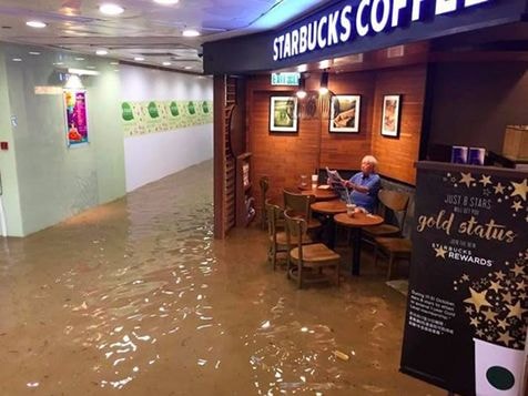 Cụ ông bình thản đọc báo trong quán cafe ngập lụt
