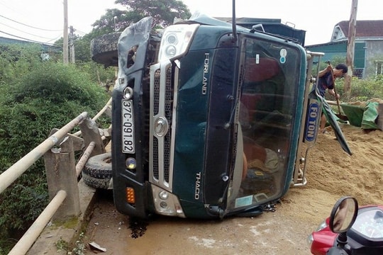 Xe tải lật ngang giữa cầu, dân trèo cabin kéo tài xế ra ngoài