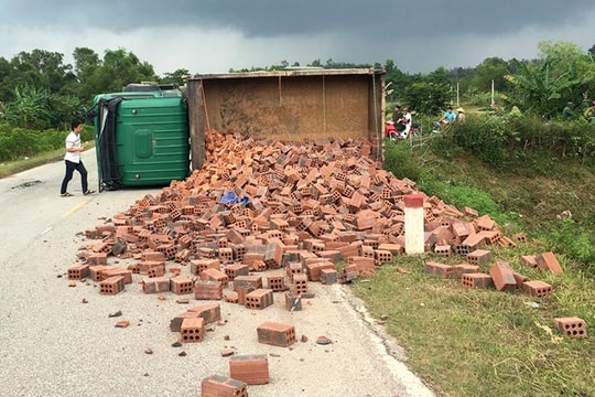 Xe tải lật nghiêng rải gạch khắp đường sau cú va chạm với xe máy