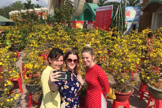 Du khách Tây diện áo dài chụp ảnh với hoa Tết