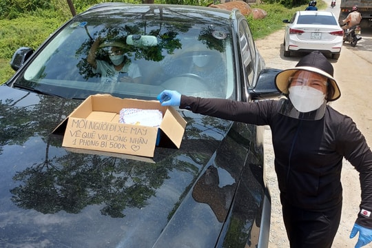 Người phụ nữ ở Nghệ An phát phong bì tiền cho người dân về quê tránh dịch bằng xe máy