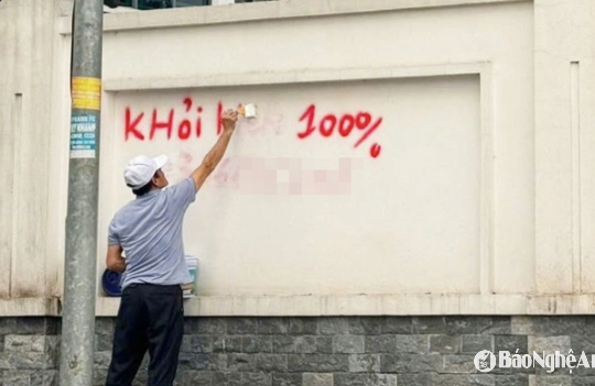 Người đàn ông xịt sơn quảng cáo lên tường ở TP.Vinh